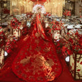 A woman walks down an ornate aisle wearing an ancient xiuhe dress in vibrant red with intricate gold embroidery and a flowing train