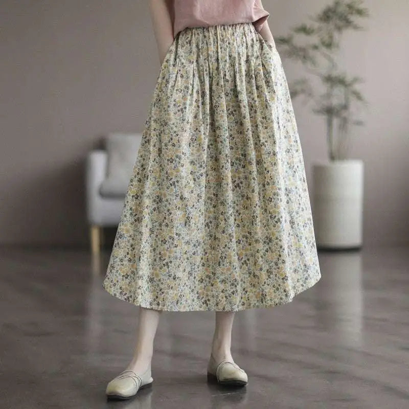A flowing cream-colored midi skirt in artistic floral washed cotton with a delicate floral pattern in soft yellow and green tones