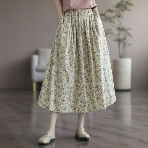 A flowing cream-colored midi skirt in artistic floral washed cotton with a delicate floral pattern in soft yellow and green tones