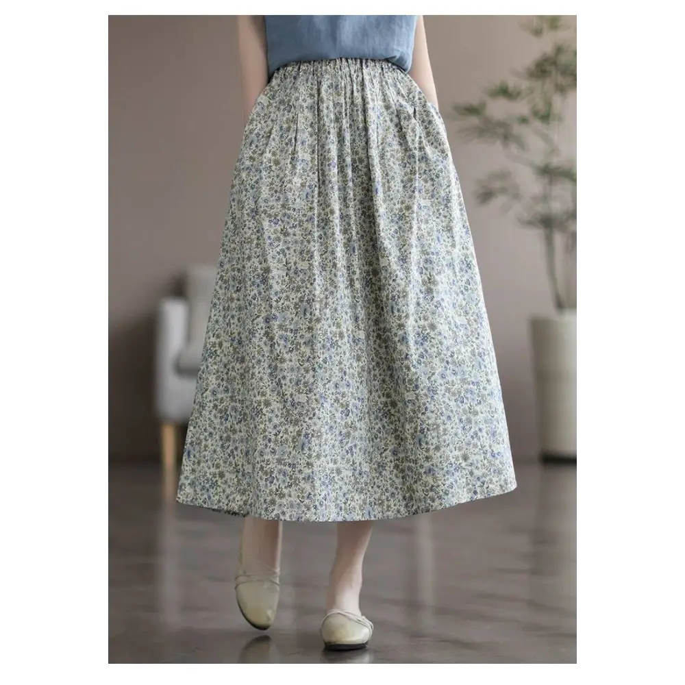 A flowing cream-colored midi skirt in artistic floral washed cotton with a delicate floral pattern in soft yellow and green tones