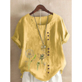 A soft yellow linen printed casual top with embroidered dandelion designs and a row of brown buttons down the front