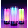 Three cylindrical led ambient light gaming bluetooth speakers with translucent bodies glowing in vibrant gradient hues