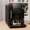 Black de’longhi small coffee machine with automatic touch screen and sleek modern design for espresso brewing