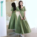 A woman wears an avocado green sisters satin midi dress with puffed sleeves and a square neckline