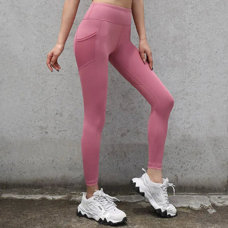 Pink high-waisted gym sport seamless leggings made of smooth stretchy fabric with side pockets designed for athletic use.