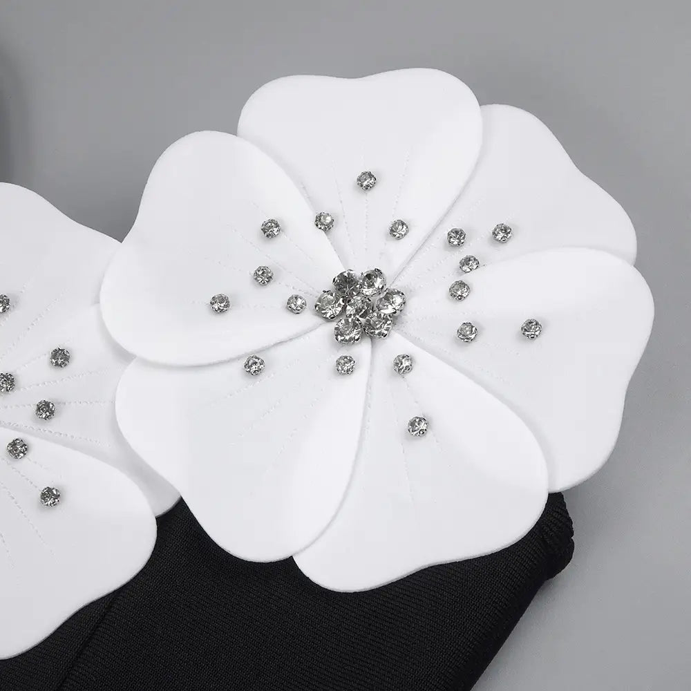 white floral hair accessory adorned with sparkling rhinestones complements the black backless bandage white floral gown highlighting the backless bandage chest design.