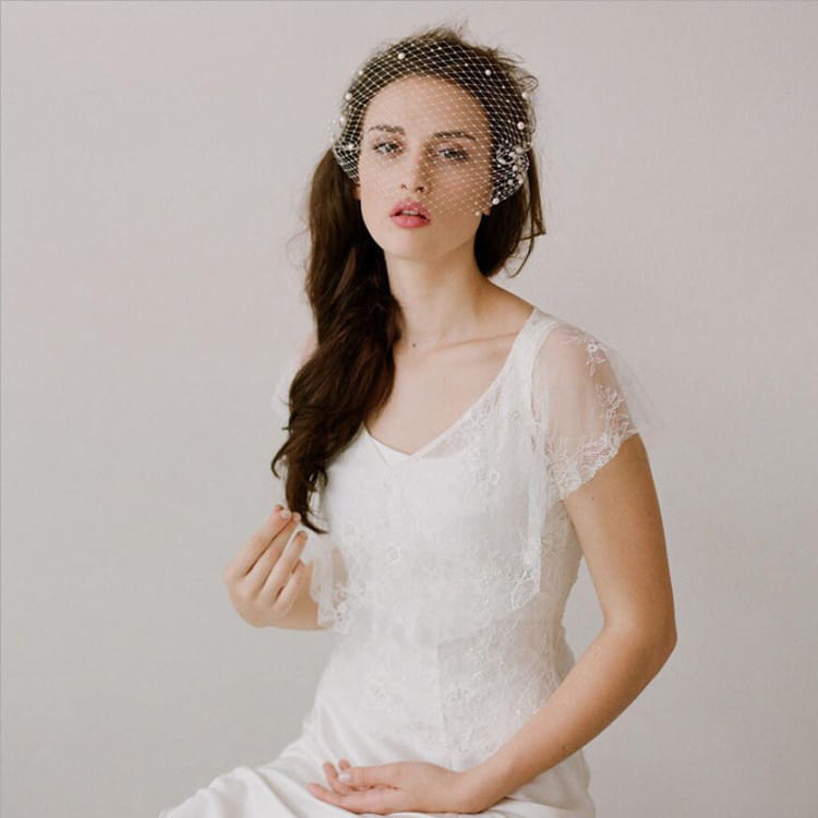 A delicate white lace bridal veil pearl with small pearl embellishments on a large hole mesh hair comb.
