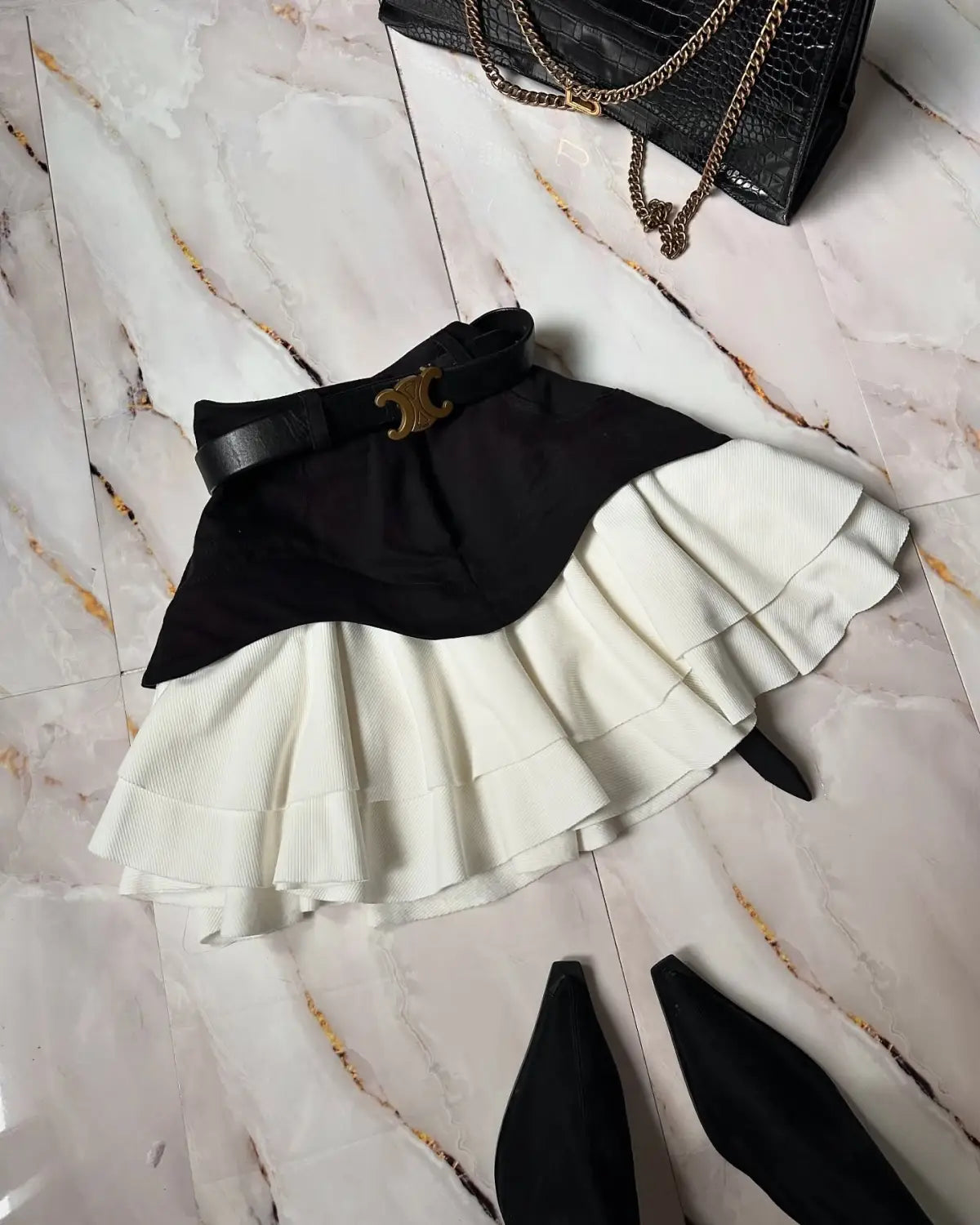 beige two tone ruffled high waist tiered skirt with black and white ruffled mini layers and a black belt featuring a gold toned c shaped buckle