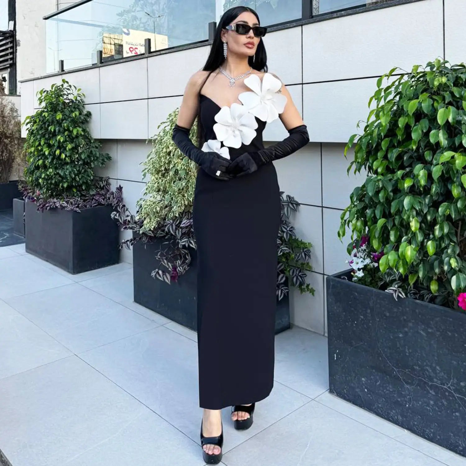 black backless bandage gown featuring a strapless design with a bandage chest white material adorned with large white floral appliqués