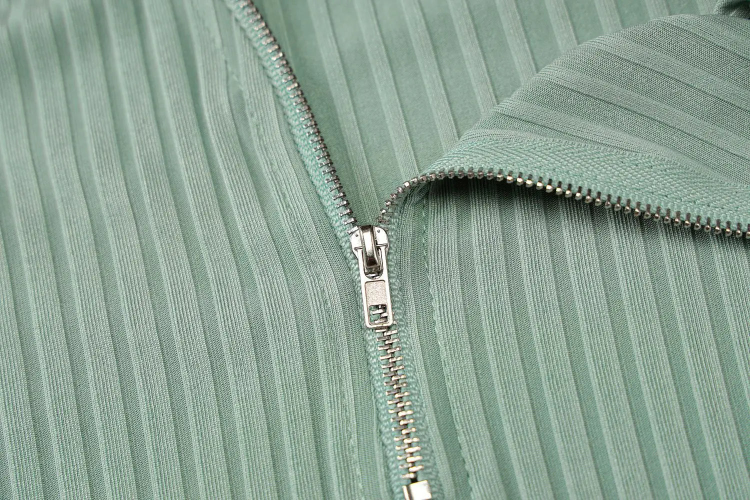 a silver-toned zipper with a branded pull tab set into the ribbed mint-green fabric of an olive green stripe knitted women sleeveless dress