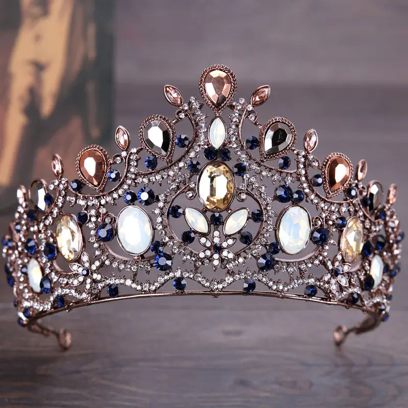 An ornate vintage elegant sapphire and diamond bridal crown tiara featuring blue, rose gold, and clear crystals set in an intricate silver-toned metal framework.