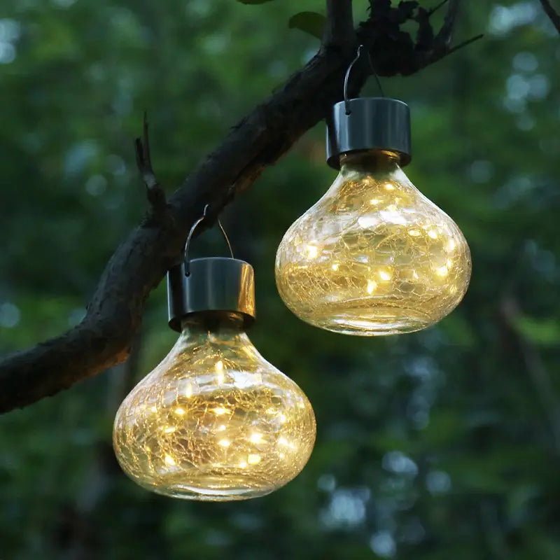Two solar-powered garden lights with crackled glass globes and metallic caps providing a small night light ambient light for outdoor use.
