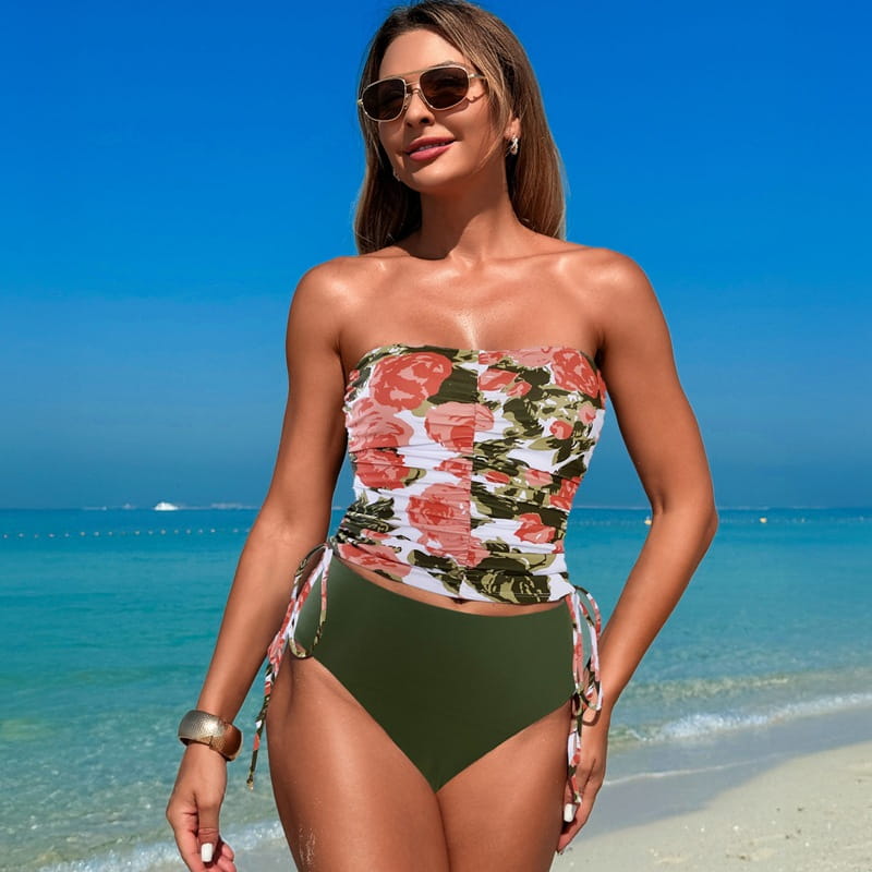 A strapless hot spring tight swimsuit bikini featuring a vibrant floral pattern with pink roses and green leaves on a white background paired with solid olive green high waisted bottoms.
