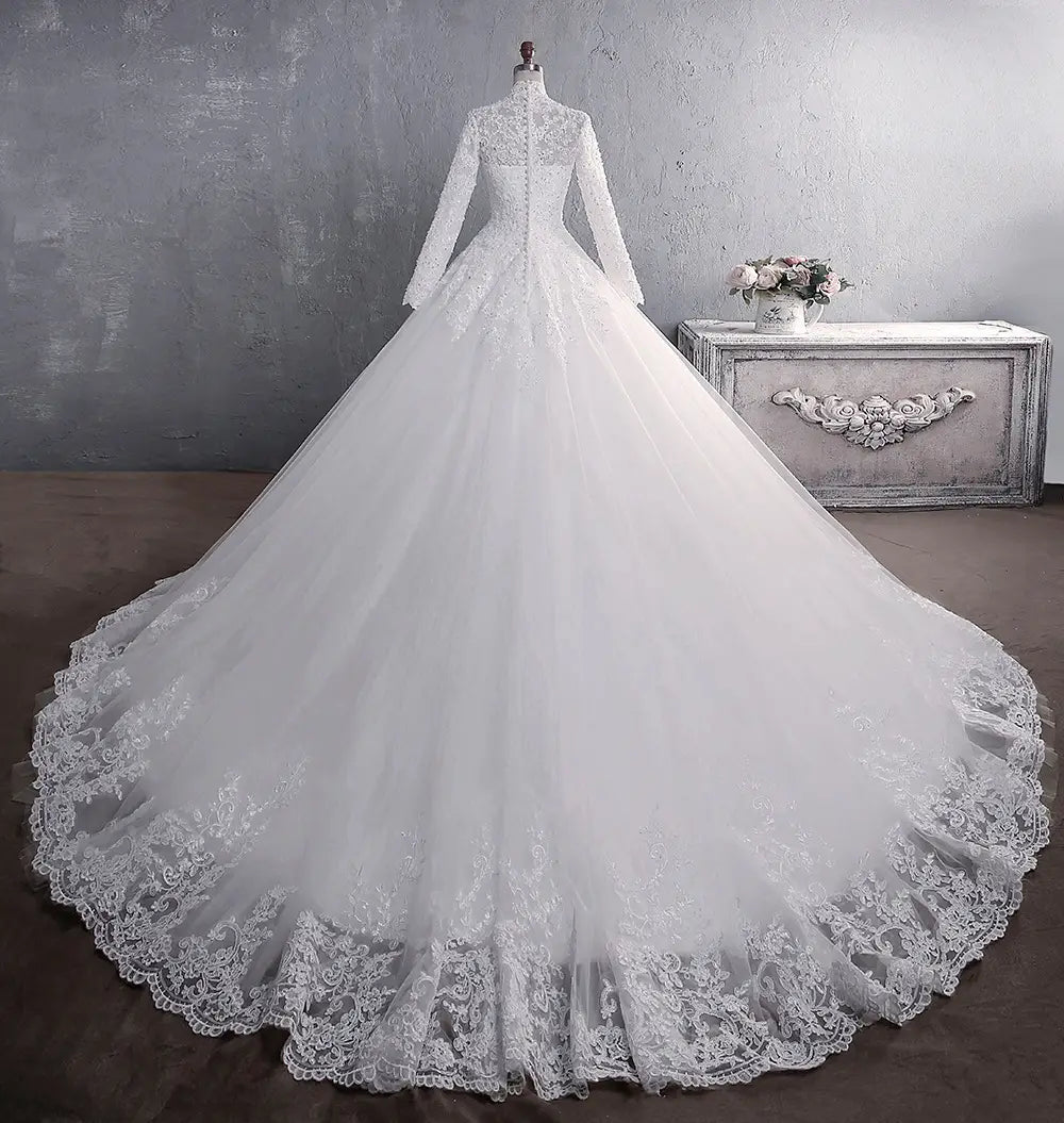 A white lace wedding dress bridal gown with long sleeves, a high neckline, intricate floral embroidery, and a large tail.