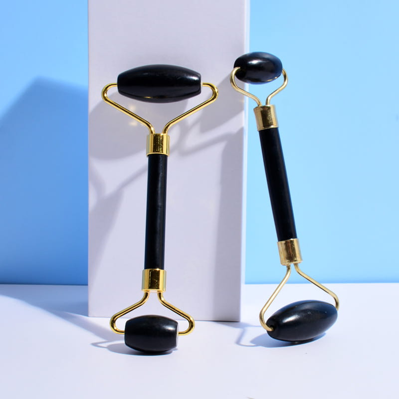 Black obsidian beauty face care massage jade roller with a gold-toned metal frame and black onyx handle for care massage jade applications.