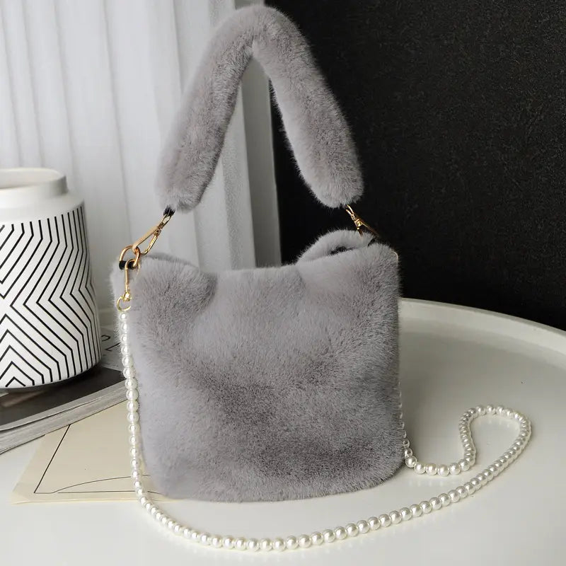 Soft light gray checkerboard plush bucket bag featuring a faux fur material with a matching fuzzy handle and a delicate pearl chain design strap.