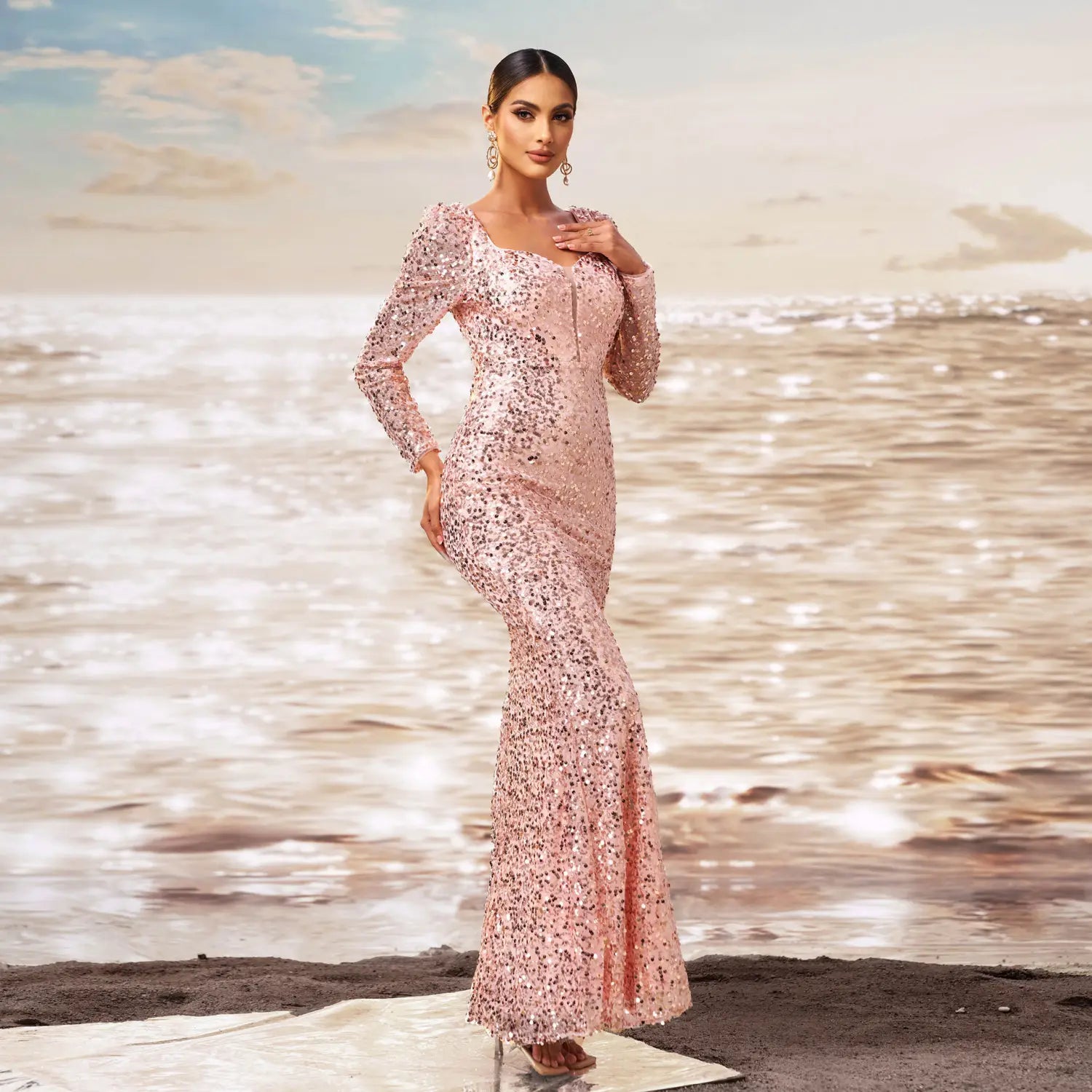 A shimmering pink long sleeve sequined sheath fishtail evening dress with a square neckline and mermaid-style silhouette.