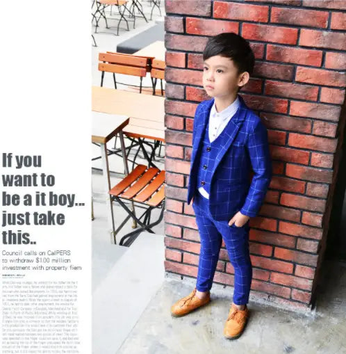 a young boy wearing a vibrant blue plaid children’s three-piece fashion suit with matching trousers and vest paired with light brown leather shoes showcasing a stylish comfort suit for formal occasions