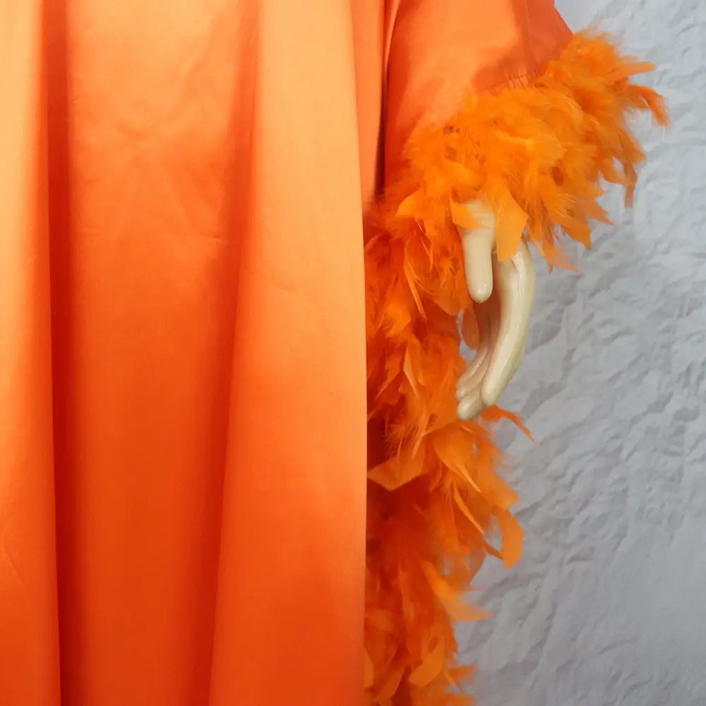 Vibrant orange feather boa draped over a mannequin arm showcasing a loose dress luxury fully designed for elegant style.