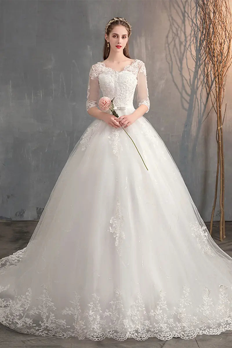 A white lace wedding dress with three-quarter length sleeves and a voluminous trailing high waist skirt.