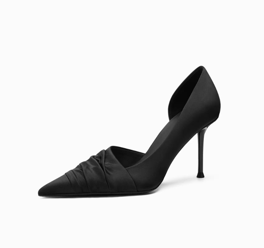 A black cloth satin high heel pump with a pointed toe and ruched detailing in a formal style.