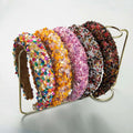 A collection of baroque colorful headbands adorned with sparkling gemstones in vibrant multicolored, orange, pink, silver, and brown hues
