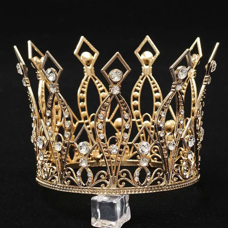 A baroque golden birthday crown with intricate filigree detailing and sparkling clear crystals for cake decoration