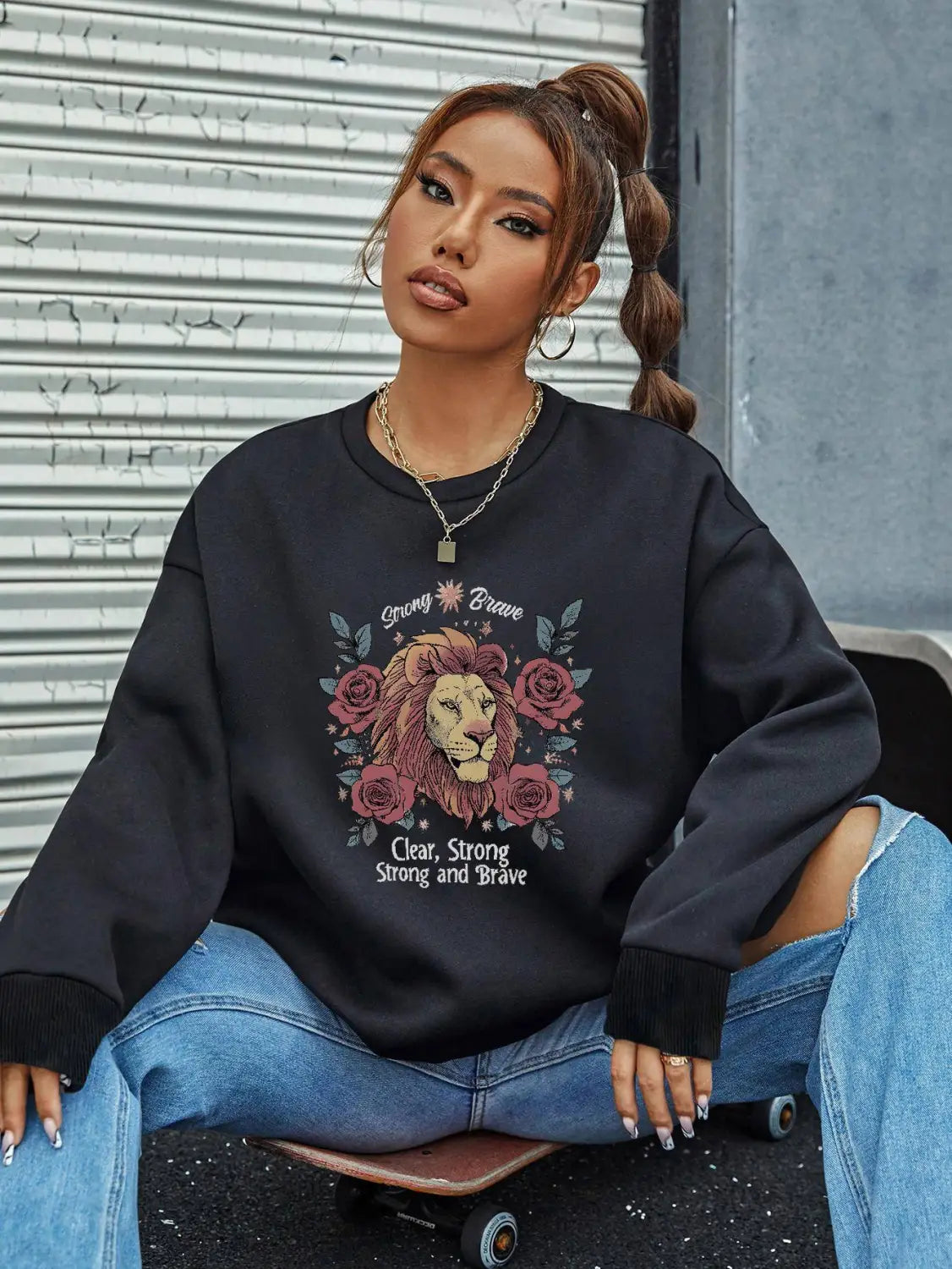 Black oversized lion rose regular fit long sleeve sweatshirt featuring strong brave text above and clear strong strong and brave text below the graphic design.