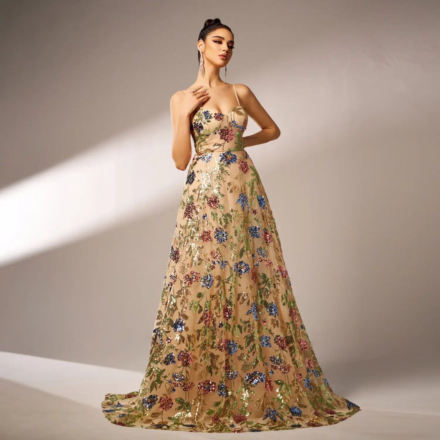 An elegant sleeveless sequined suspender evening dress in shimmering champagne color featuring intricate floral embroidery in vibrant blues reds and greens.