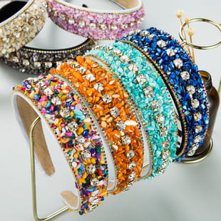 a collection of colorful baroque vintage court style headbands adorned with sparkling rhinestones and sequins in pink, gold, black, teal, orange, blue, and multicolored patterns