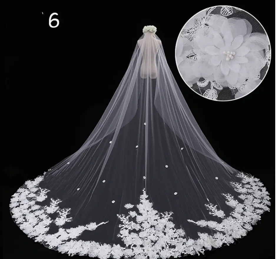A delicate white lace wide style bridal wedding dress veil with intricate floral embroidery and pearl-like embellishments along its trailing edge featuring a hair comb attachment.