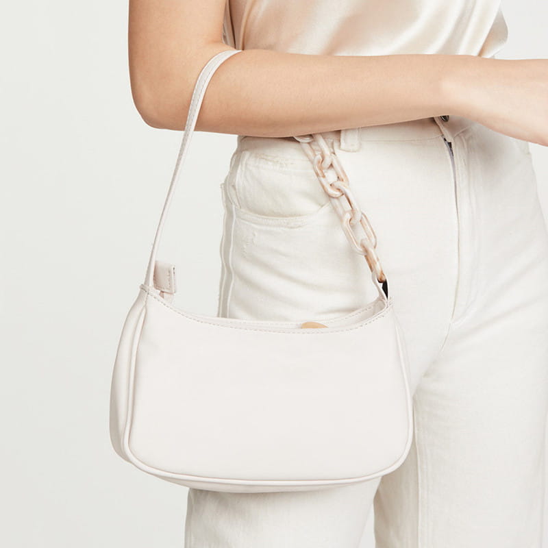 A sleek off-white leather trendy small crocodile bag featuring a slender strap and an acrylic chain detail.