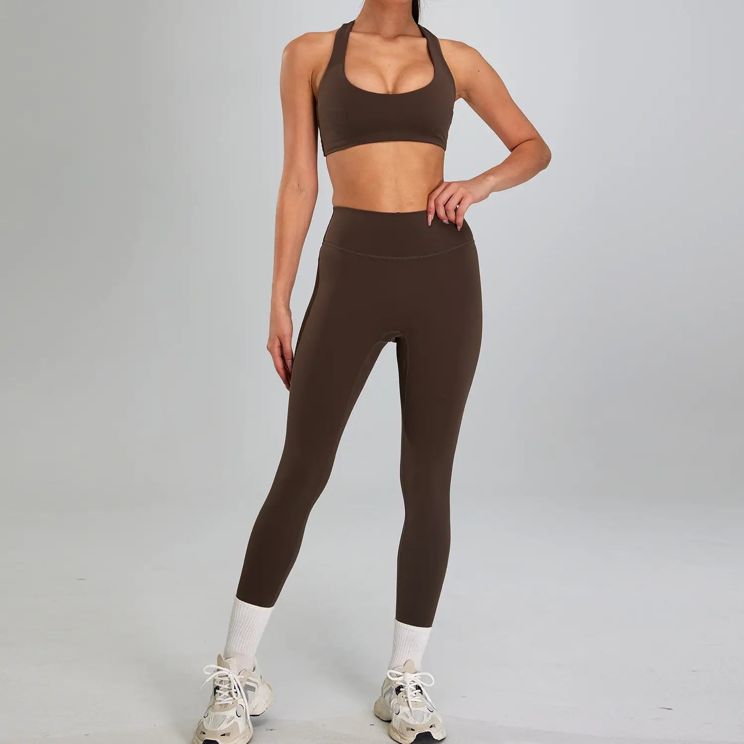 a matching brown athletic two-piece sports suit outdoor featuring a supportive crop top and high-waisted leggings made from stretchy form-fitting material for outdoor running nude use