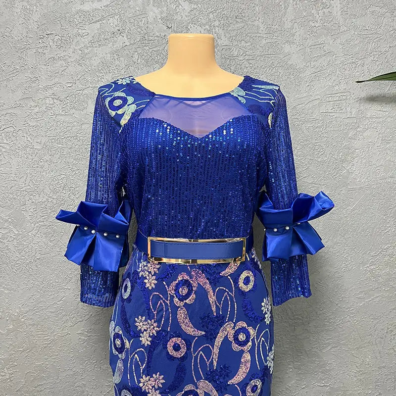 A vibrant royal blue half sleeve slim evening dress with round neck shirt design, featuring sequined fabric, floral embroidery, sheer mesh panels, and satin bow accents at the cuffs.