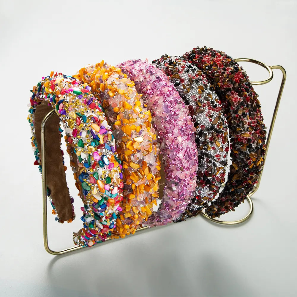 a collection of five baroque colorful headbands adorned with sparkling gemstones, sequins, and beads in vibrant hues including rainbow multicolors, pink, orange, silver, and brown