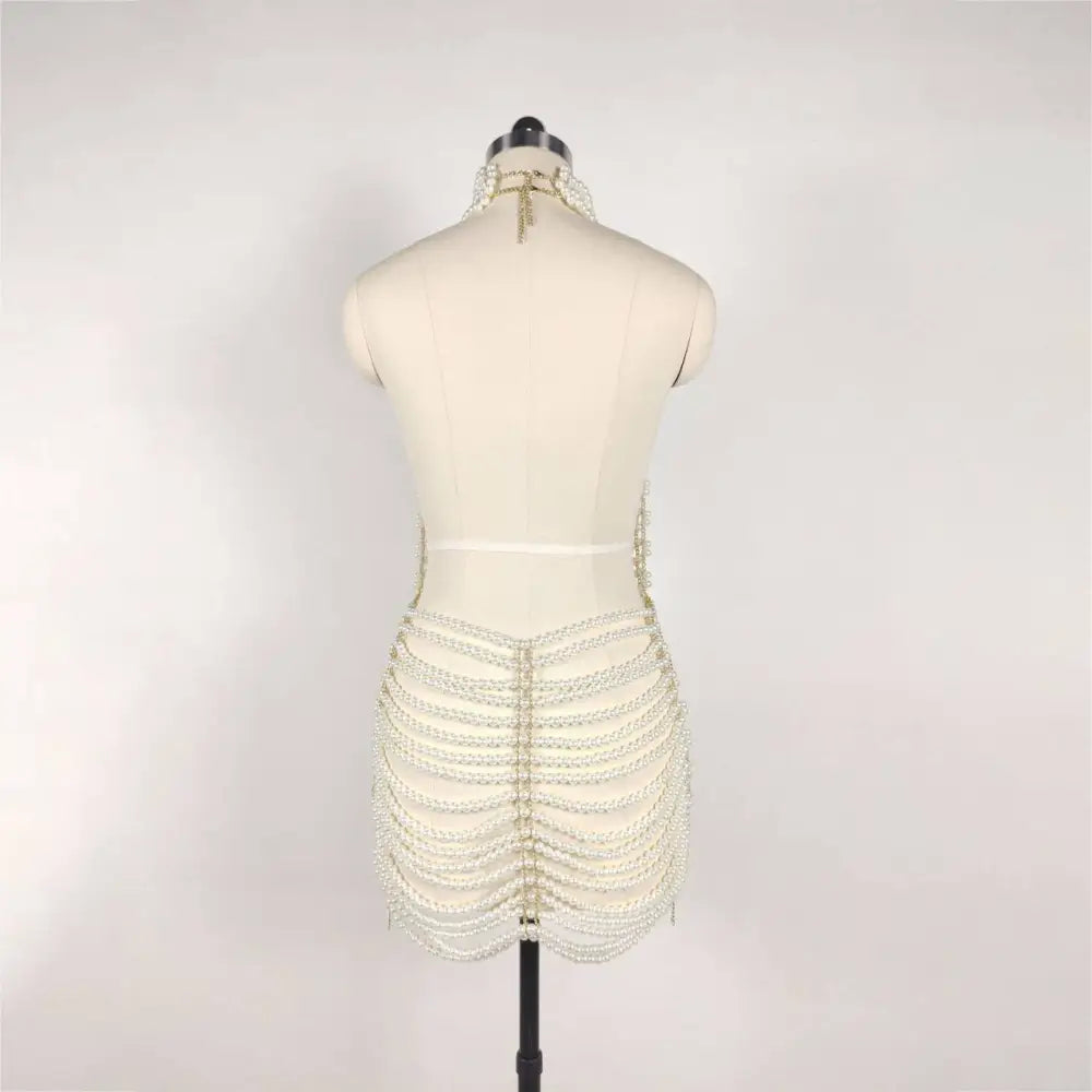 Back view of a shimmering white beaded halter fashion pearl chain dress with skeletal pearl strands for fashion party banquet