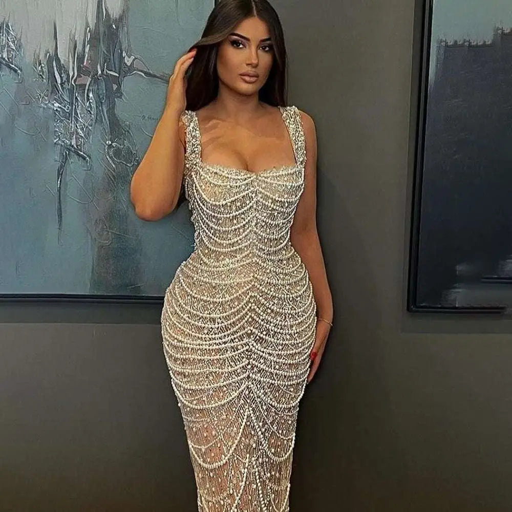 A beaded nude elegant sling luxury gown featuring intricate white and silver beads cascading down a form-fitting silhouette