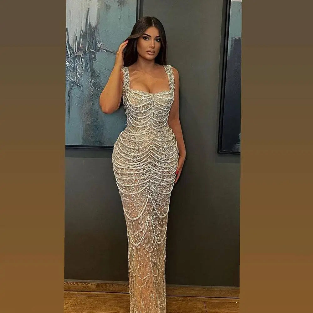 Elegant sling luxury gown in metallic silver with intricate cascading beadwork on a floor-length beaded nude elegant gown