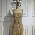 Elegant sling luxury beaded nude gown featuring a fitted gold silhouette with cascading pearls and crystal embellishments