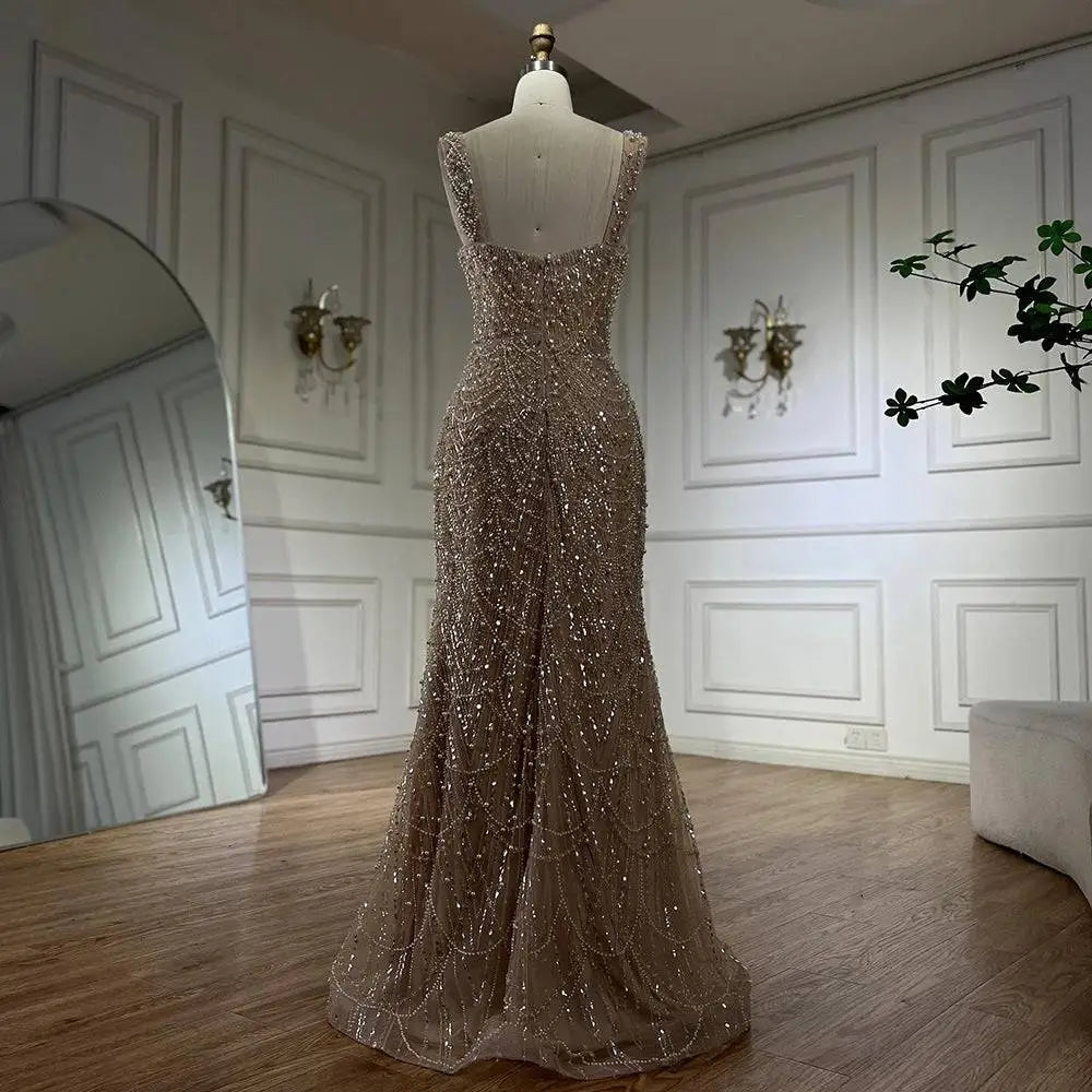 A shimmering gold beaded nude elegant sling luxury gown featuring a fitted bodice and flowing mermaid skirt on mannequin