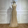 A shimmering gold beaded nude elegant sling luxury gown featuring a fitted bodice and flowing mermaid skirt