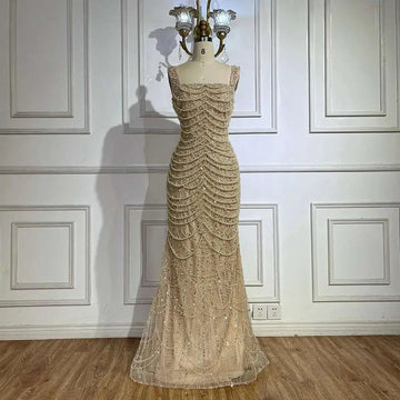 A shimmering gold beaded nude elegant sling luxury gown featuring a fitted bodice and flowing mermaid skirt