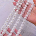 White lace trim with delicate floral patterns and pearl embellishments on a beaded trailing yarn wedding bridal veil with broadband hair comb