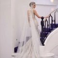 A shimmering white beaded trailing yarn wedding bridal veil with broadband hair comb over a fitted silhouette gown