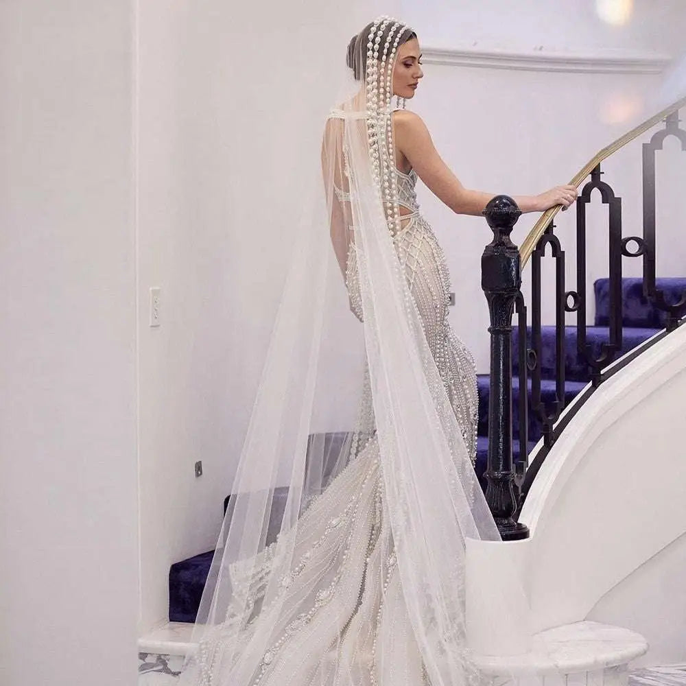 A shimmering white beaded trailing yarn wedding bridal veil with broadband hair comb and pearl embellishments