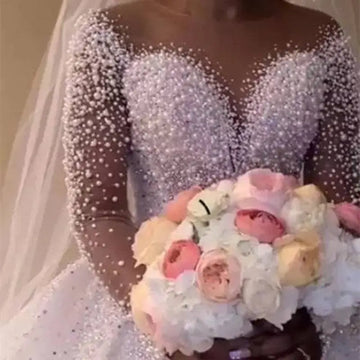A sparkling white beaded ball gown wedding dress with long sheer sleeves and a fitted bodice