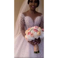 A sparkling white beaded ball gown wedding dress with long sheer sleeves and a fitted bodice