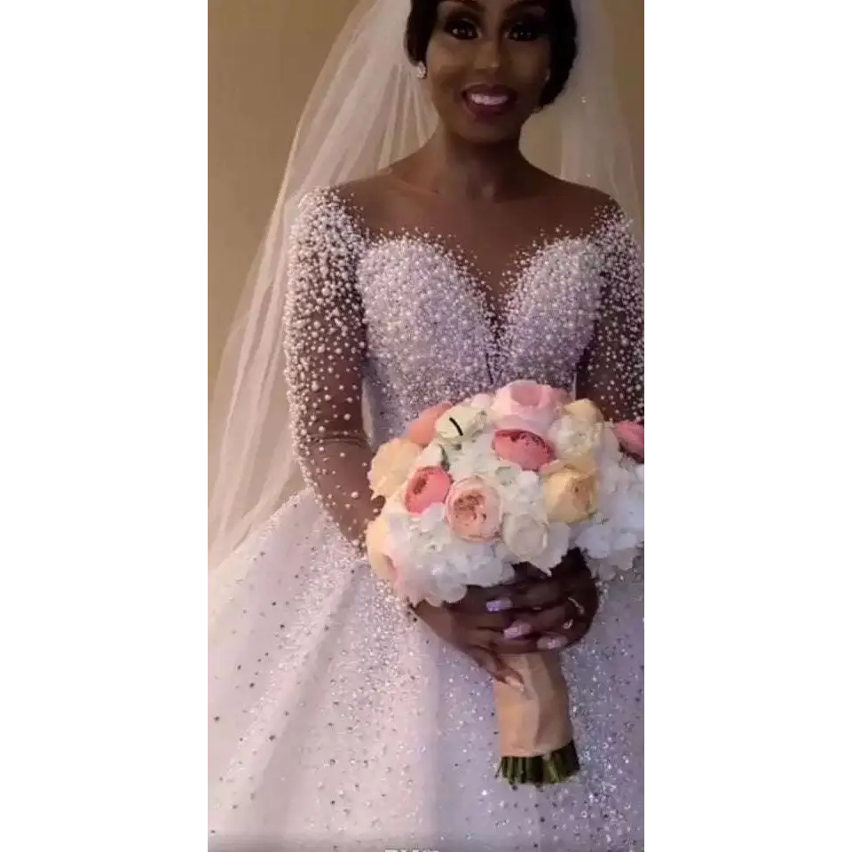 A sparkling white beaded ball gown wedding dress with long sheer sleeves and a fitted bodice