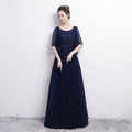A navy blue banquet evening dress with a lace bodice, sheer sleeves, and flowing beaded white tulle skirt for spring