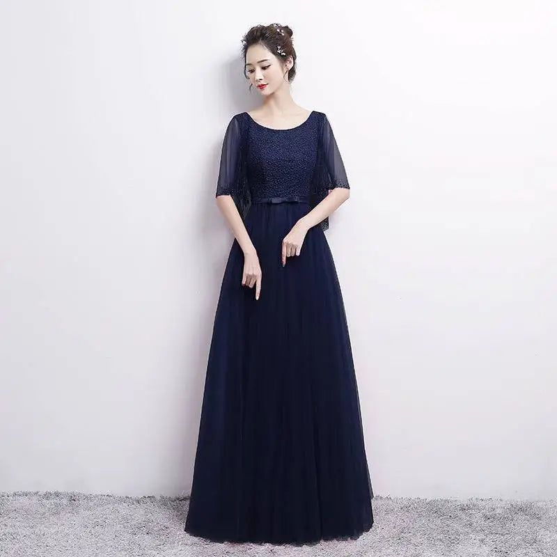 A navy blue banquet evening dress with a lace bodice, sheer sleeves, and flowing beaded white tulle skirt for spring
